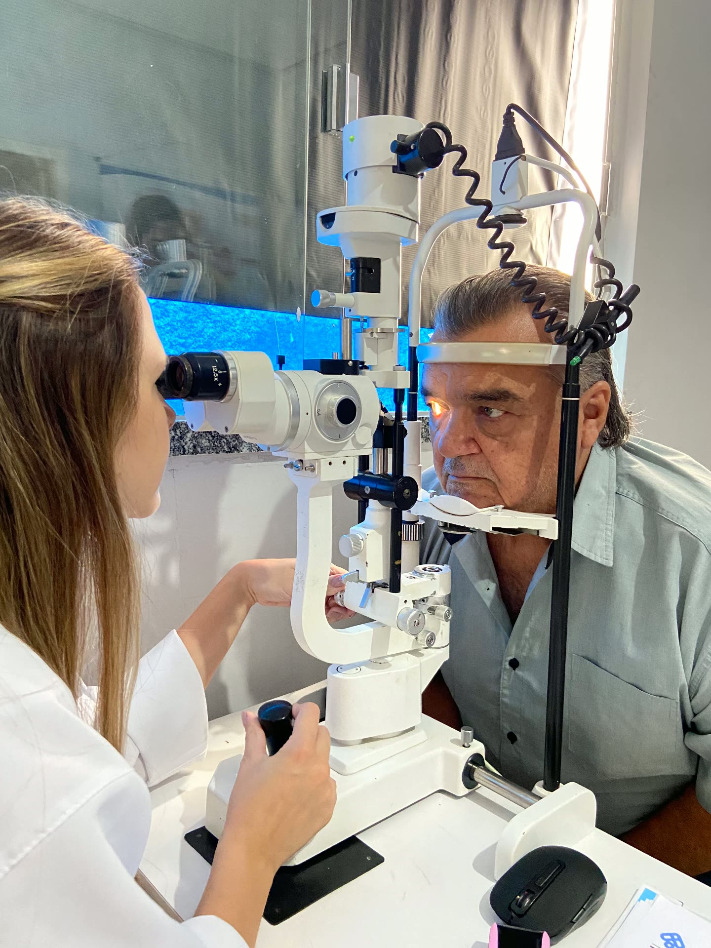 Paciente sendo examinado em lâmpada de fenda por profissional do instituto